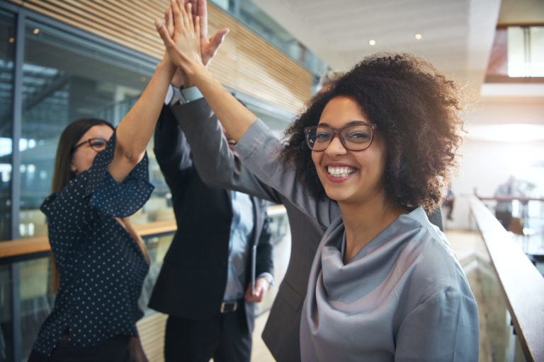 Smiling black businesswoman giving high five to ofiice team